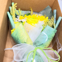 Bouquet of flowers in a box with green and yellow ribbons